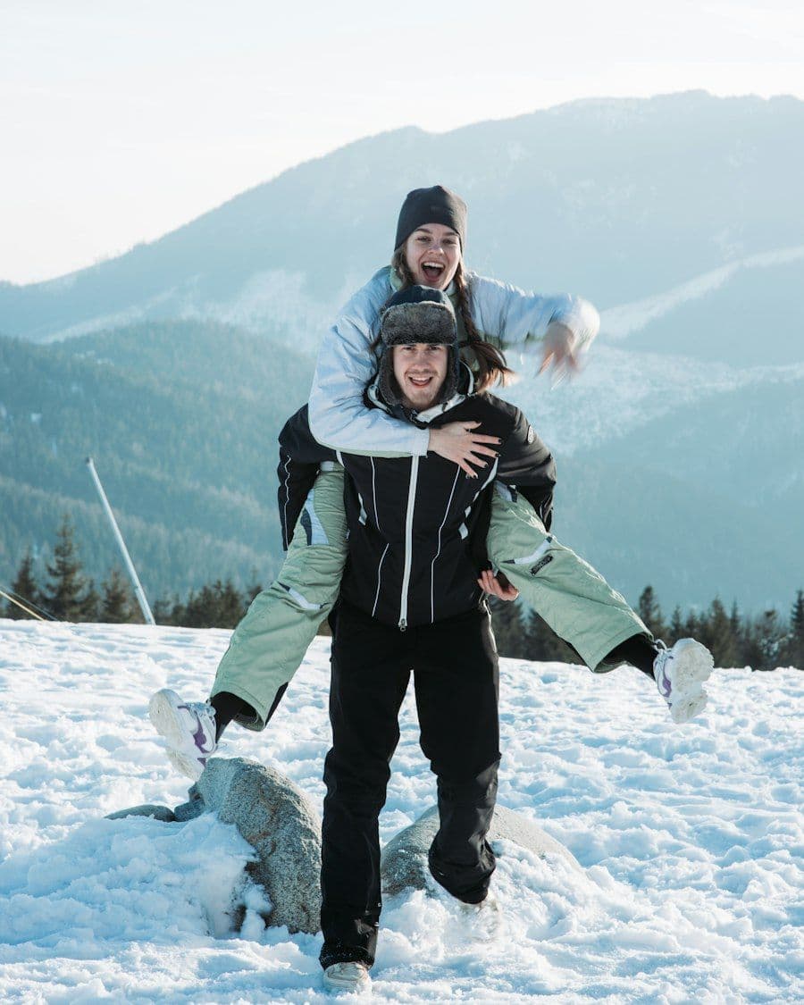 Casal sorridente na neve, com montanhas ao fundo