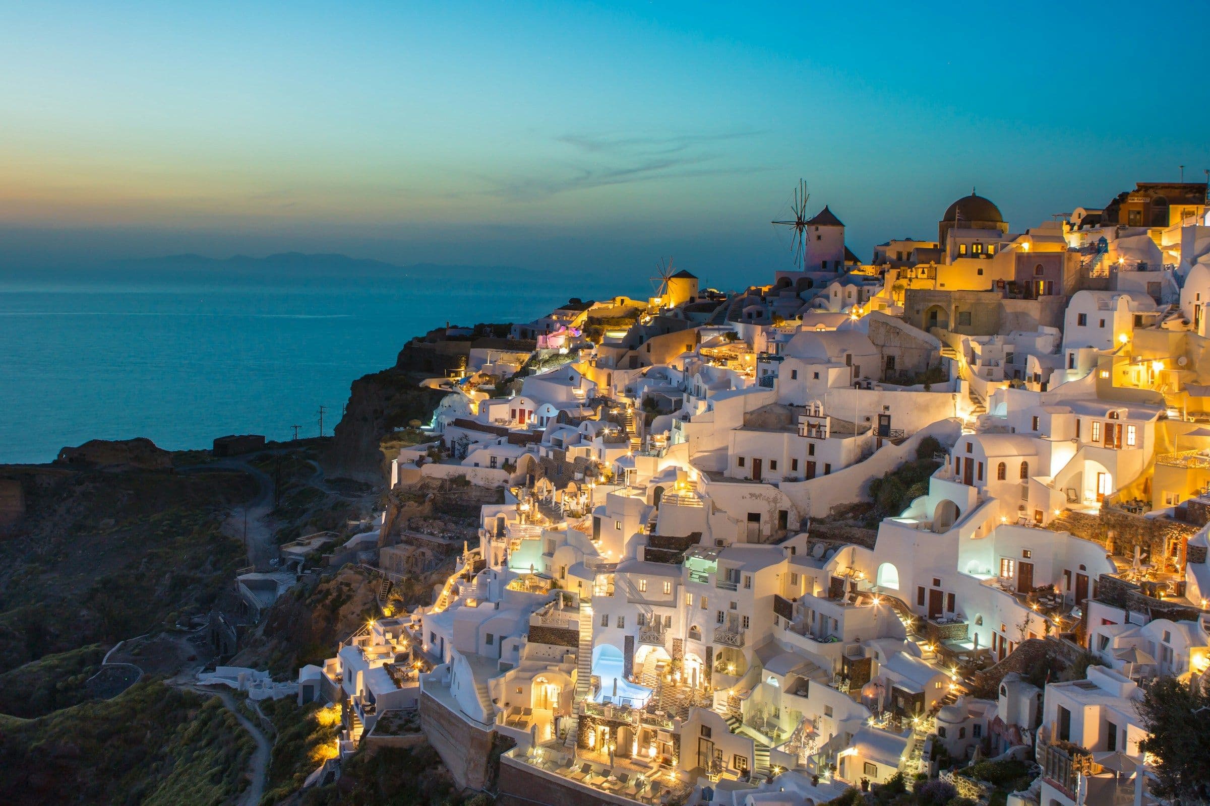 Casas brancas e igrejas de cúpula azul em Oia, Santorini, ao entardecer