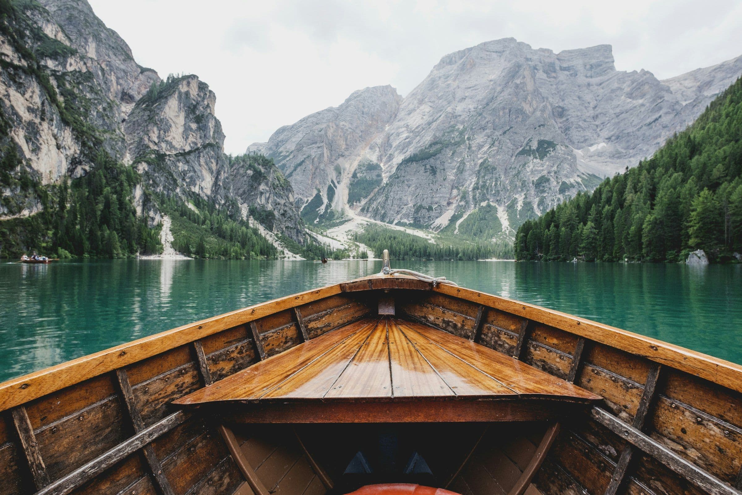 Barco de madeira em lago alpino cercado por montanhas nas Dolomitas